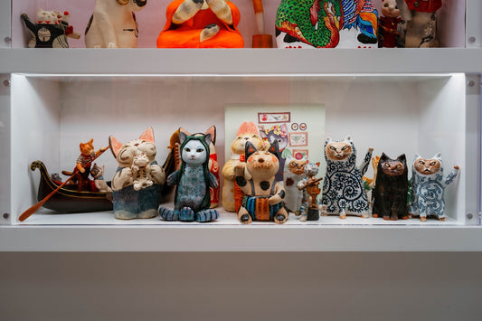 Collection of diverse cat figurines displayed on shelves.